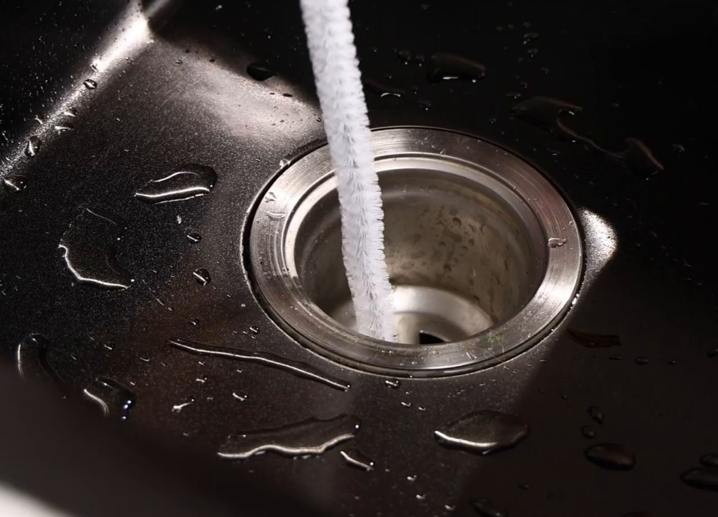 Clogged sink drain with DrainFix tool inserted — before cleaning